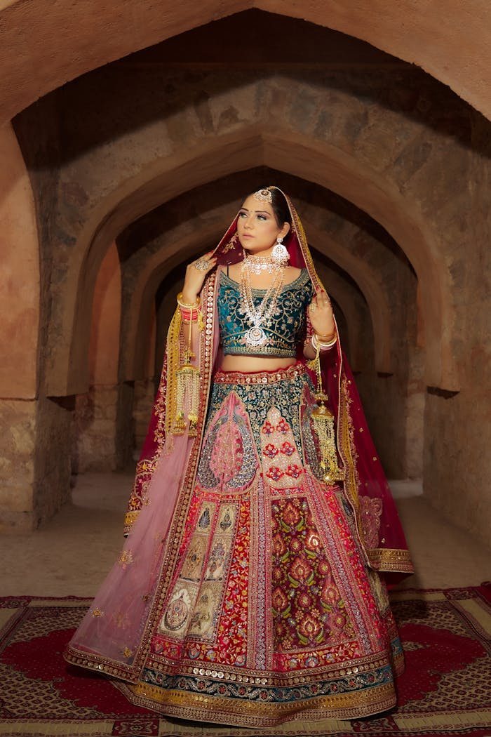 Full shot of a woman in traditional Indian clothes standing in historical architecture.