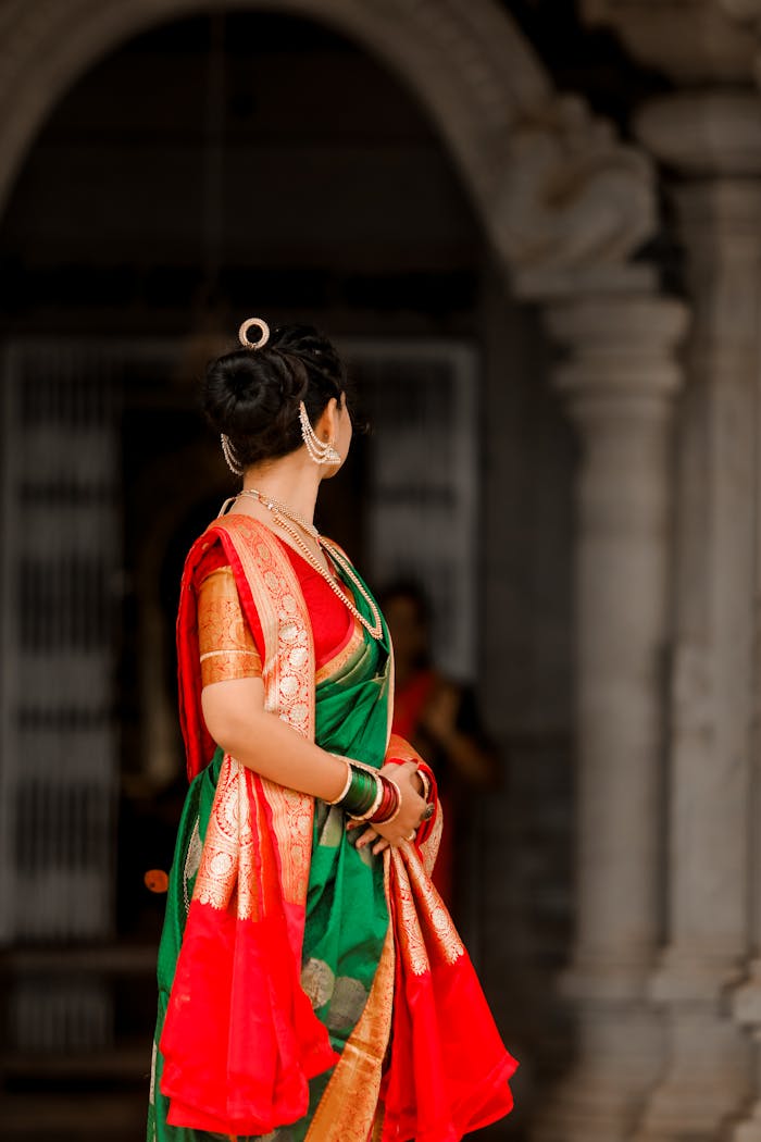 A woman in a traditional sari stands gracefully at the entrance of a historic temple, showcasing cultural elegance.