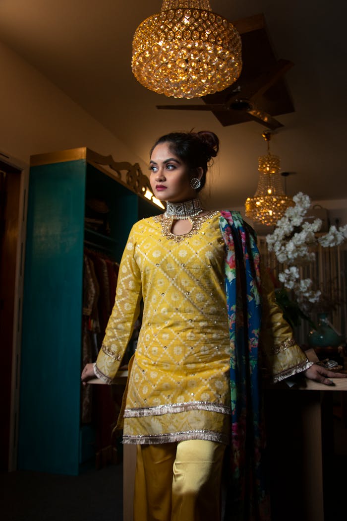 Portrait of a woman in vibrant yellow traditional attire with elegant decor.