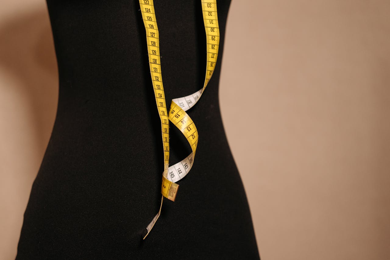 Elegant black mannequin with yellow measuring tape, perfect for fashion design themes.